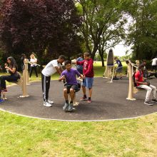 range of outdoor gym equipment proludic in use by young adults in outdoor green space