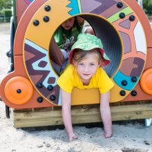 girl leaning on patterned grafic games play equipment on sand